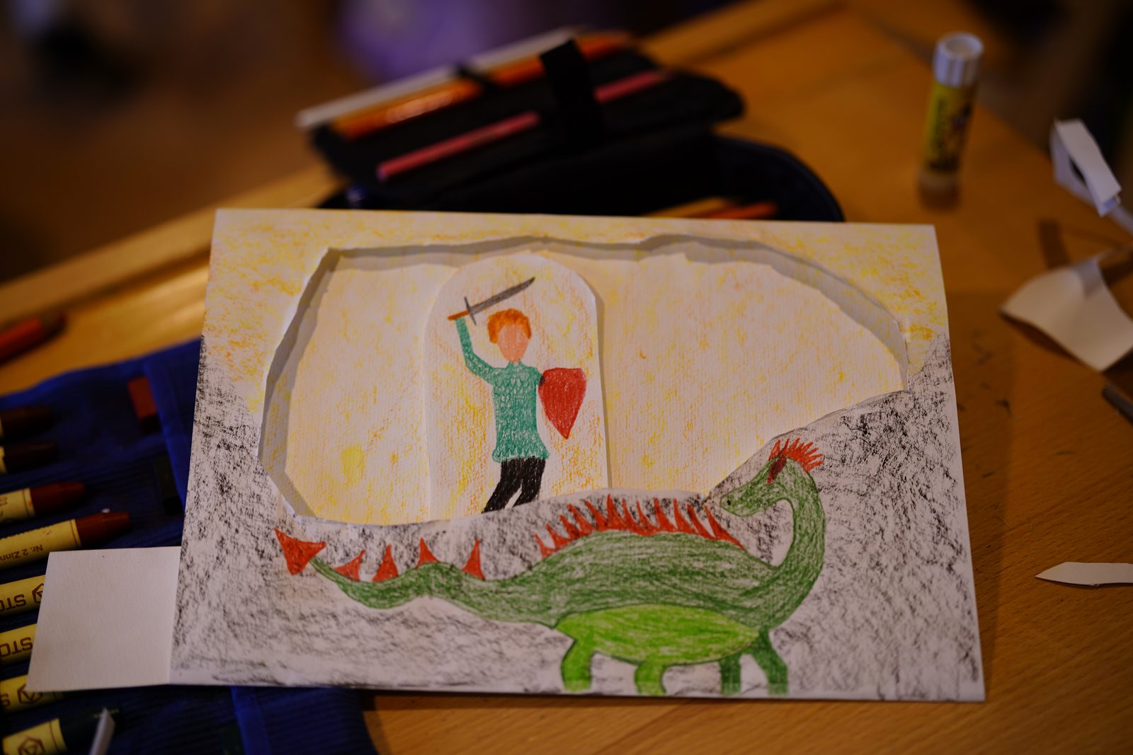 Selbst gestaltetes Schiebebild der vierten Klasse: ein Ritter mit erhobenem Schwert vor einem grünen Drachen.